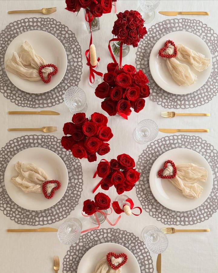 Red roses and heart bead napkin rings valentines table decor ideas from @theoldhouseonmain with elegant gold flatware and delicate glassware