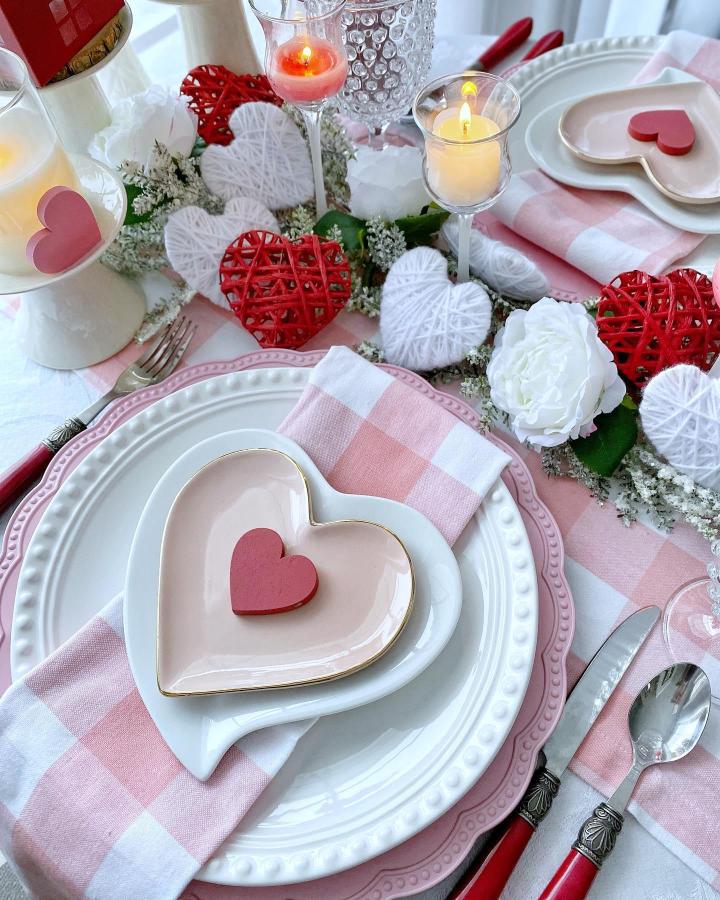 Pink and red heart-shaped plates with checkered napkins and candles from @bloom_jennybrooks for valentines table decor ideas
