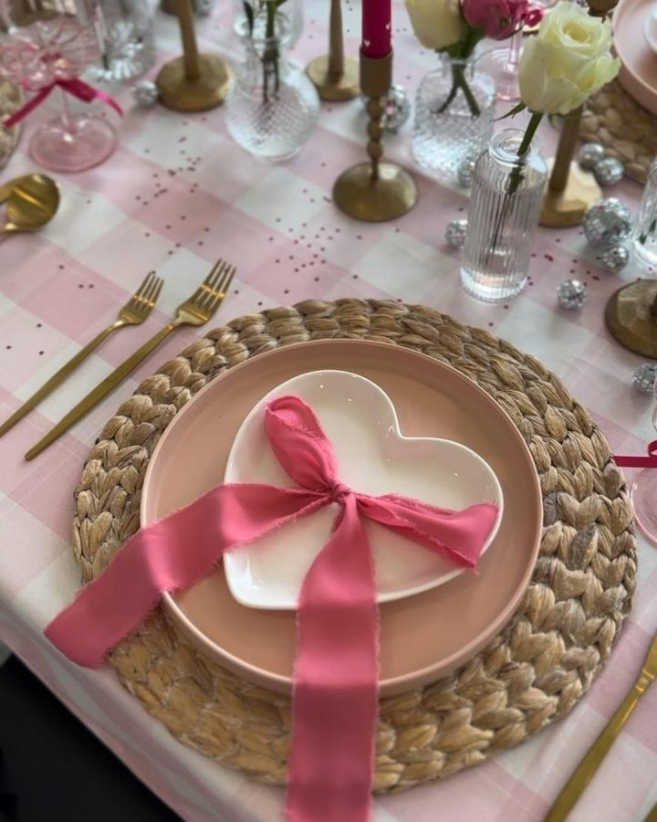 Natural woven charger plate with pink plates and heart dish tied with coral ribbon valentines table decor ideas from @kelsikendel.