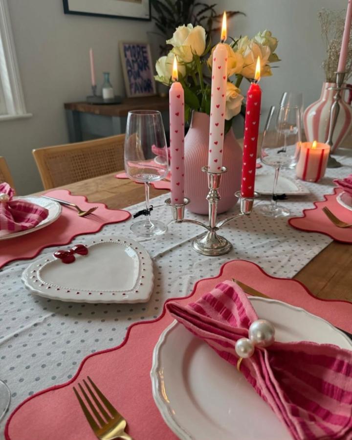Pink and red heart patterned candles on silver candelabra with white roses on table from @almostmakesperfect for valentines table decor ideas.