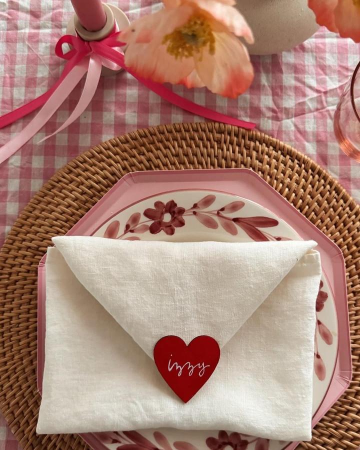 Red heart shaped place card on white linen napkin over floral pink plates valentines table decor ideas from @spotmyhouse.