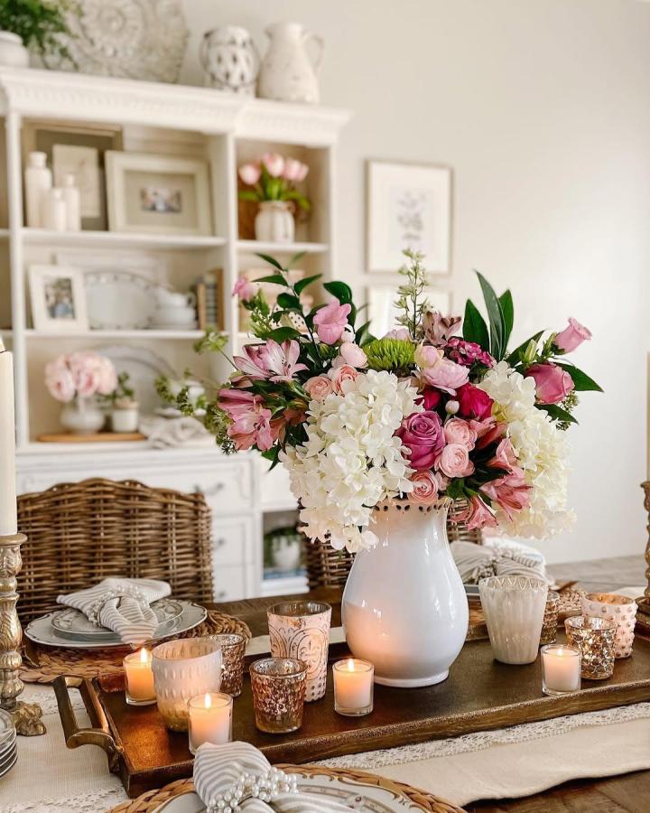 White and pink floral centerpiece with candles on dining table from @dining_delight for valentines table decor ideas.