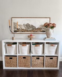 white woven and sea grass basket inserts in white ikea kallax unit from @casa.arantes.style featuring leather detail and cozy natural textures