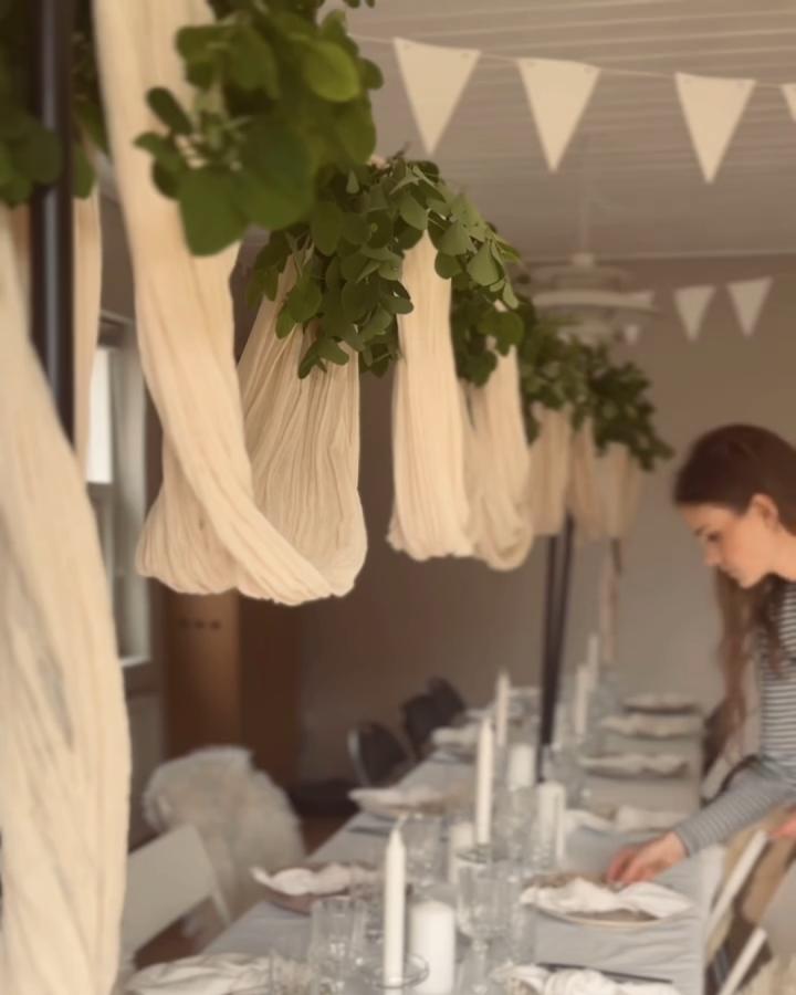Cream fabric and lush greenery hanging from black Ikea Helgeo clothes rail from @linekohsel. A soft, natural floating display enhancing a wedding table atmosphere in ikea wedding hacks & ideas.