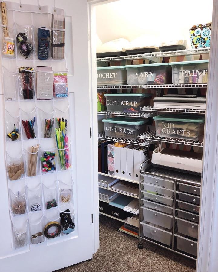 Clear labeled craft closet with teal bins from @lelaburris. Door pockets and wire shelves keep supplies organized.