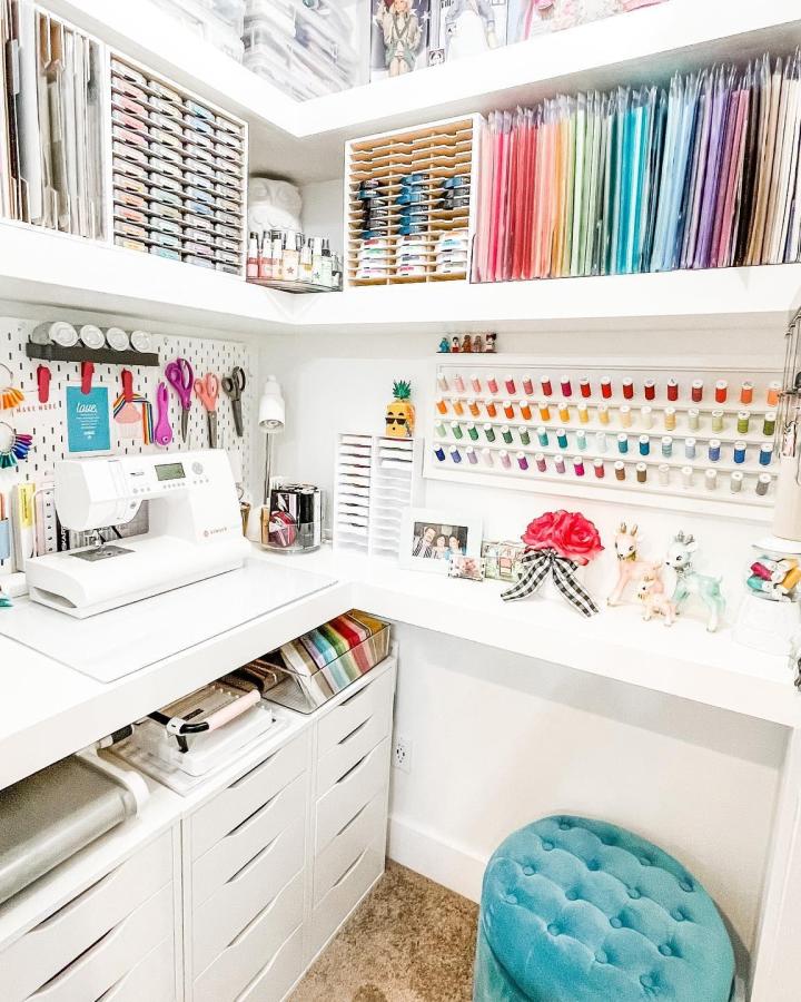 turquoise tufted stool craft closet from @laura_evangeline. Bright ribbon wall and white shelving.