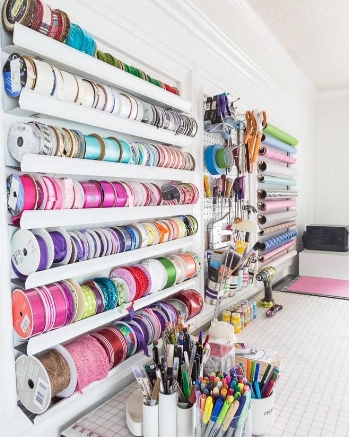 White wall-mounted ribbon storage from In My Own Style. Colorful spools and pegboard tools keep supplies tidy.