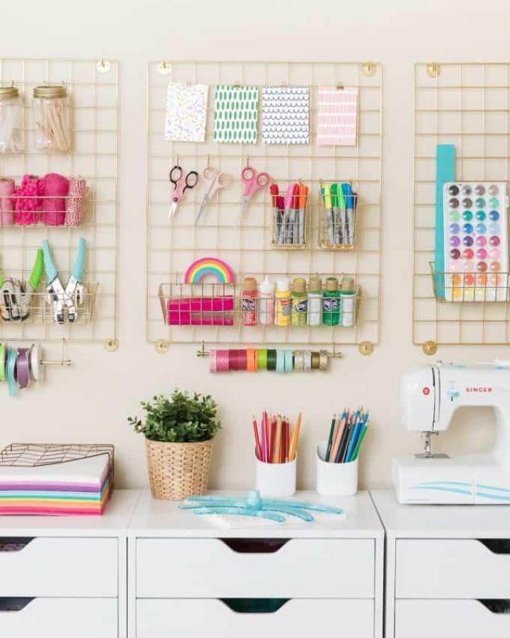 gold wire wall storage craft room organization ideas from Design Eat Repeat. White drawers and colorful supplies keep tools visible and neat.