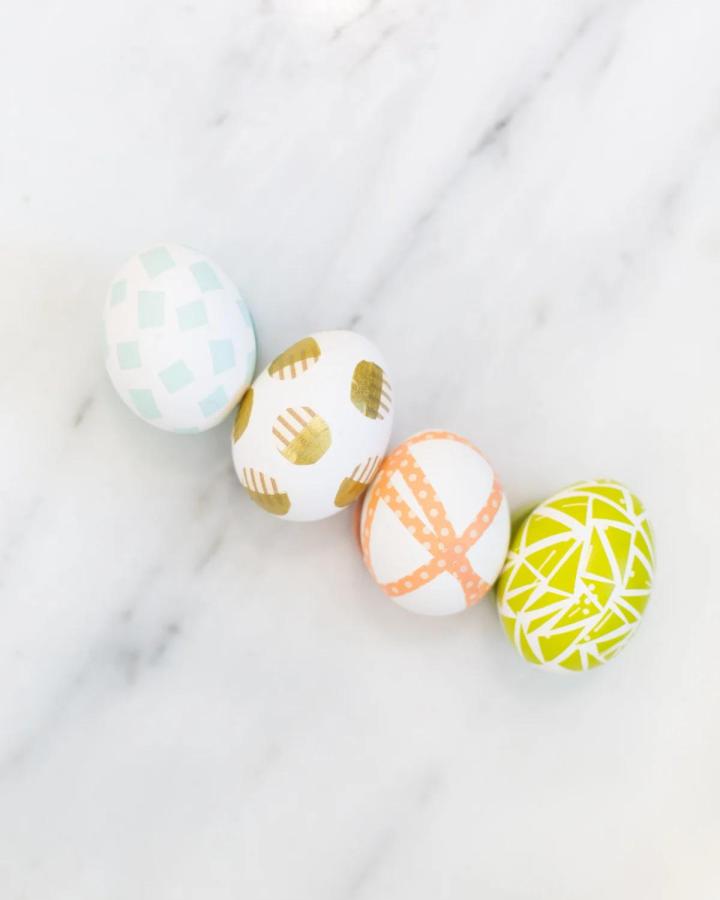 Soft pastel and gold washi tape decorated Easter eggs from Lovely Indeed featuring geometric shapes and bold color contrasts.