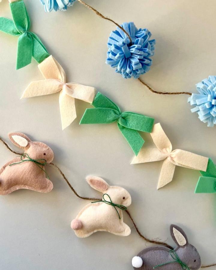 Soft pastel felt bunny garland with green bows and blue pom-poms from @sophie.diyguru Easter garland ideas with cozy handmade charm.