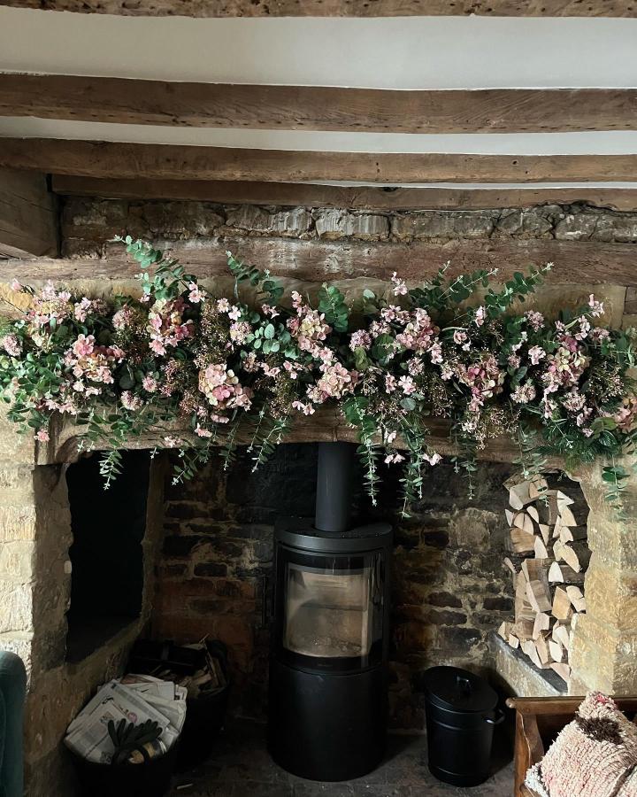 Blush pink and green floral garland on rustic wooden mantel from @isabellamillay showcasing elegant easter mantel decor ideas.