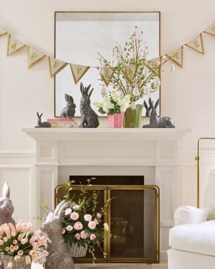 Gray rustic bunny statues and pastel flower arrangements on white mantel from Pottery Barn Easter mantel decor ideas with burlap banner.