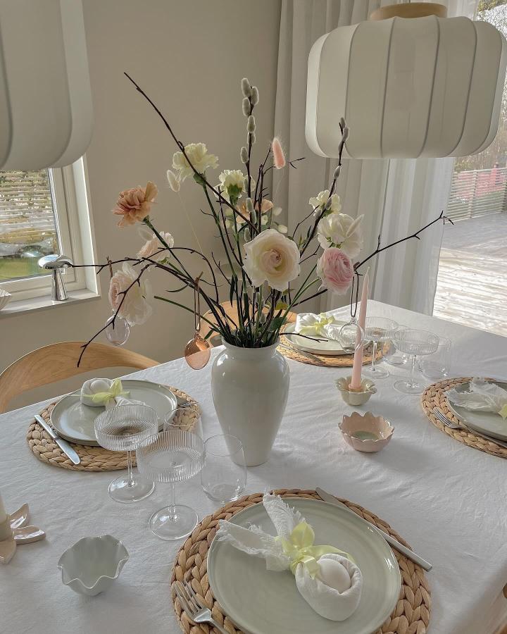 Neutral pastel floral Easter table setting with natural woven placemats and soft fabric egg decorations from @nathaliebernhardtz.
