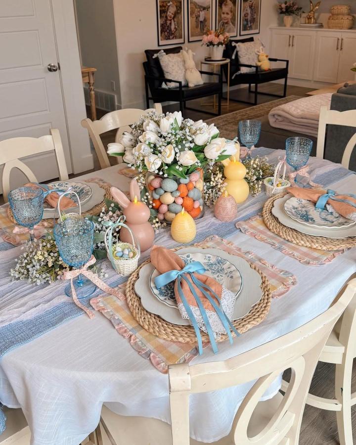 Soft pastel Easter table setting with floral plates, woven placemats, bunny candles, and tulips from @cherish.larsen.
