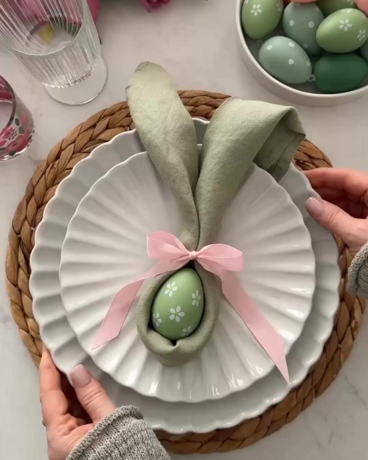 Green linen bunny ear napkin fold on white scalloped plates with pastel Easter eggs from @homewithanita easter place setting ideas