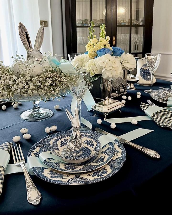Silver bunny figurines with blue and white china on dark tablecloth inspired by @noa_nene_home Easter place setting ideas.