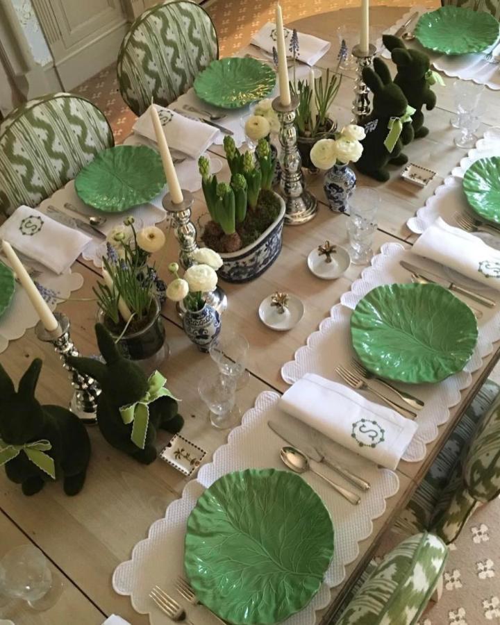 Green leaf plates and moss bunny décor on a wooden dining table with silver candlesticks from @botanicatrading for easter place setting ideas