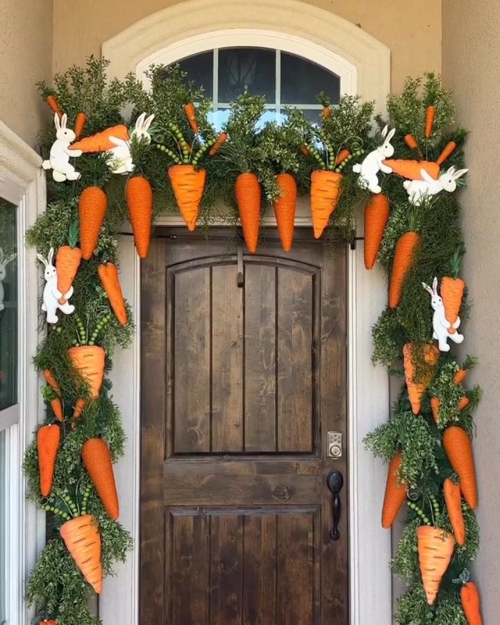 Orange carrot and white bunny garland on green faux greenery wreath around rustic wooden door easter porch decor ideas from @wreathsbywaldo.