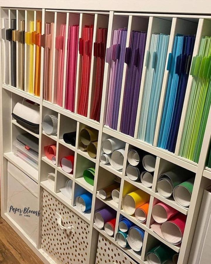 White Ikea Kallax with rainbow paper files and rolled craft materials organized neatly by @smartfundiy.
