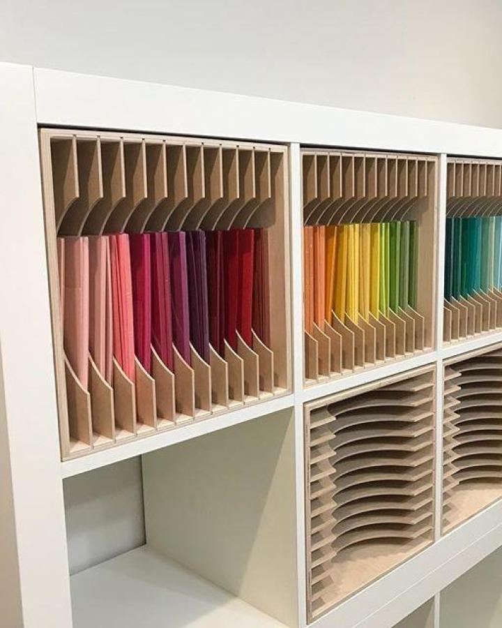 natural wood and white ikea kallax craft room ideas from @onecraftysister showing vertical paper storage slots with colorful sheets organized by hue