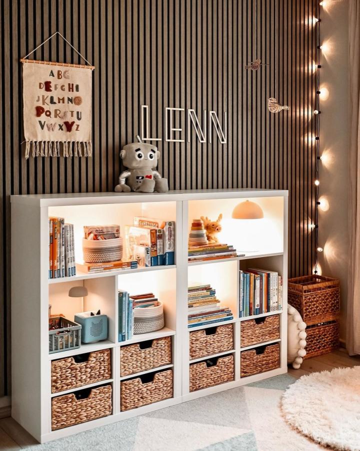Natural white Kallax toy storage from @jul1186_home. Woven baskets and lit cubbies with cozy books.