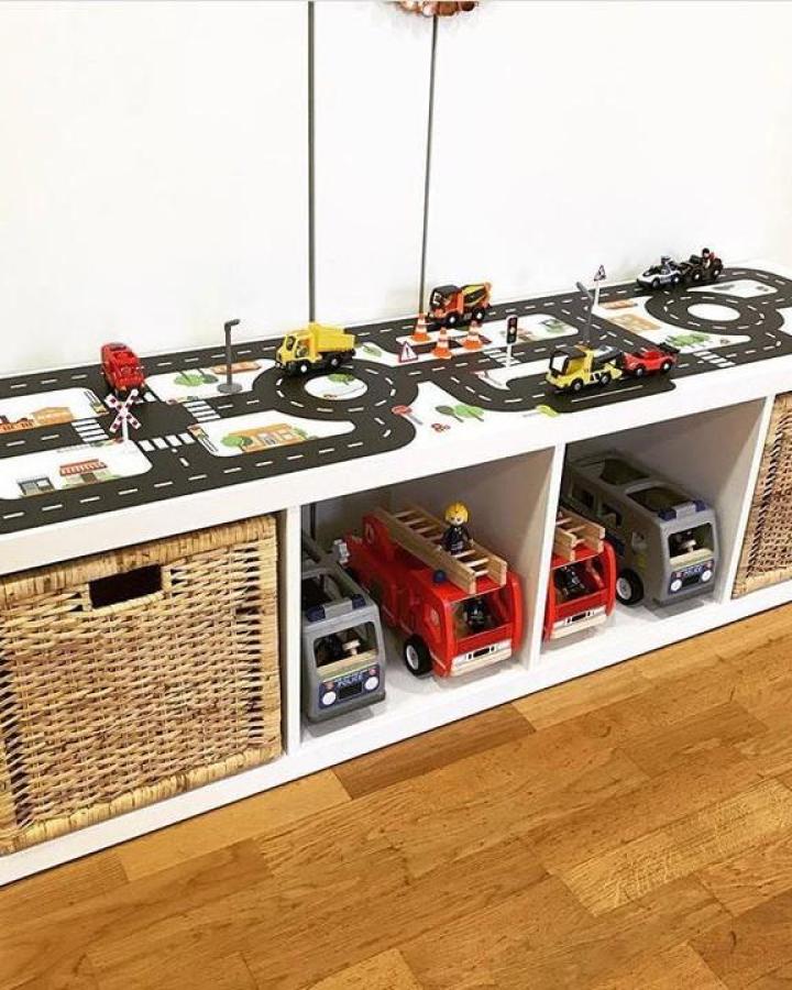 white and black toy storage unit from @limmaland. road mat top with toy trucks and baskets.