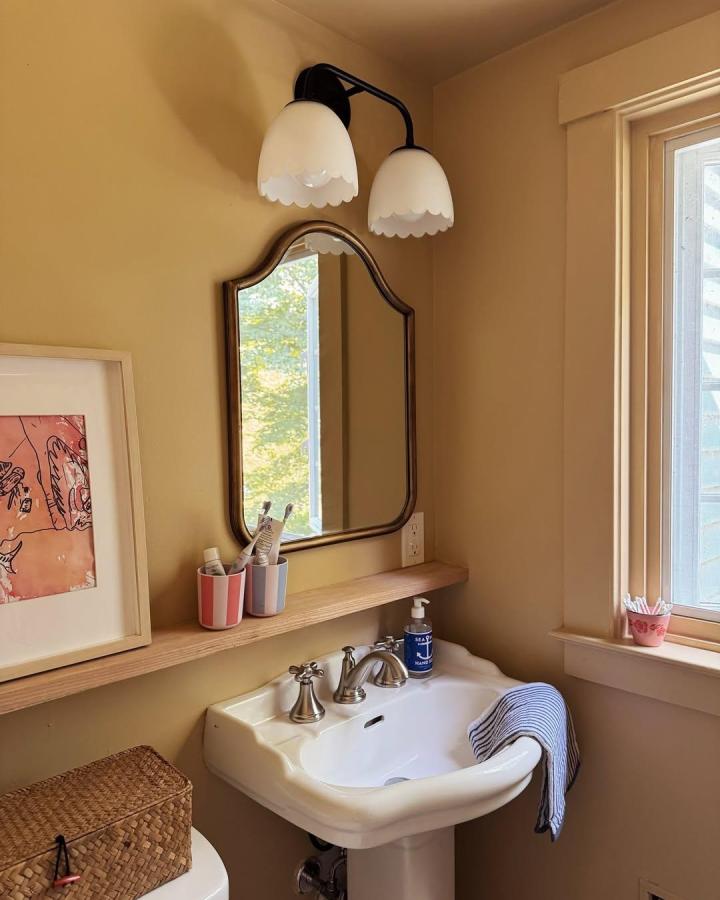 Curved vintage mirror with scalloped black light fixture in small bathroom by @almostmakesperfect highlights bathroom mirror ideas for small spaces.