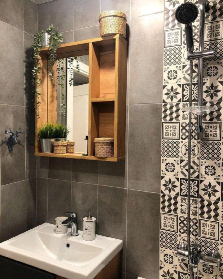 Wood-framed bathroom mirror with built-in shelves from @eder_wood showcasing bathroom mirror ideas for small spaces with plants and baskets.