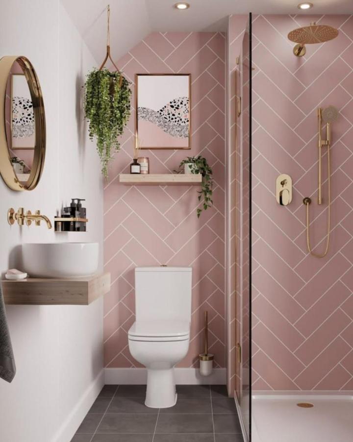 Blush pink herringbone panels bathroom wall panel ideas from @plumbworld with gold accents and greenery.