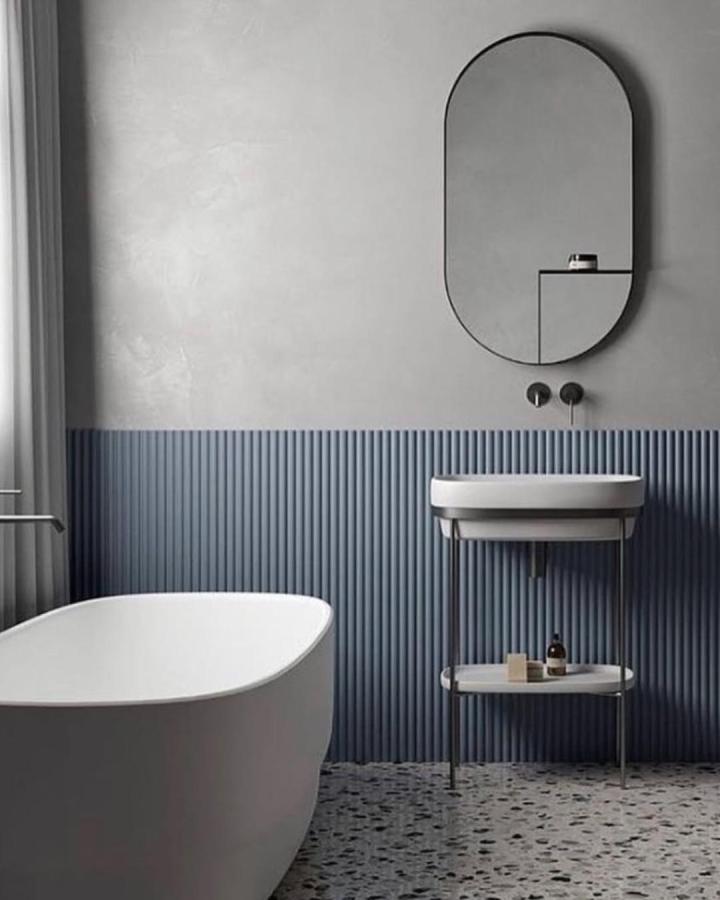 blue grooved wall panels in minimalist bathroom with white tub and mirror from @orac_usa bathroom wall panel ideas textured and calming design