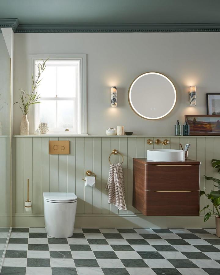 Soft green vertical panel bathroom wall panel ideas from @vado_uk with gold accents and wooden vanity in a bright space.