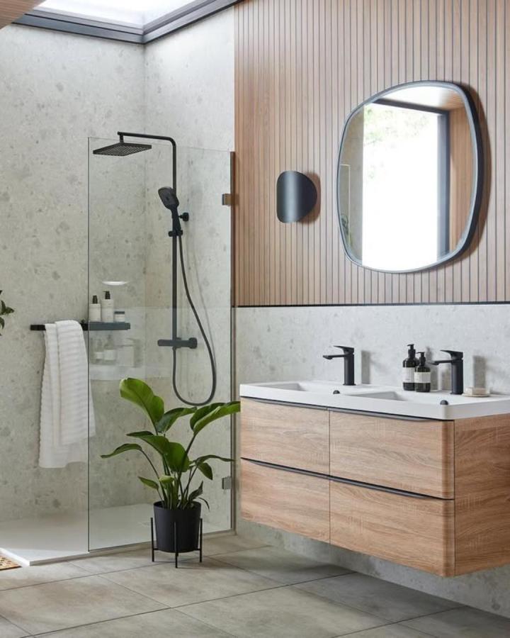 Warm vertical wood panel bathroom wall panel ideas from @vado_uk with black fixtures and natural stone tiles creating sleek modern look.