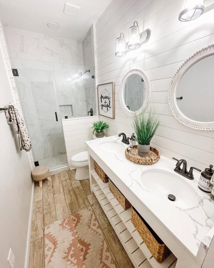 White shiplap bathroom wall panel ideas from @farmhouselovehome with rustic wood-look floors and black fixtures create cozy charm.