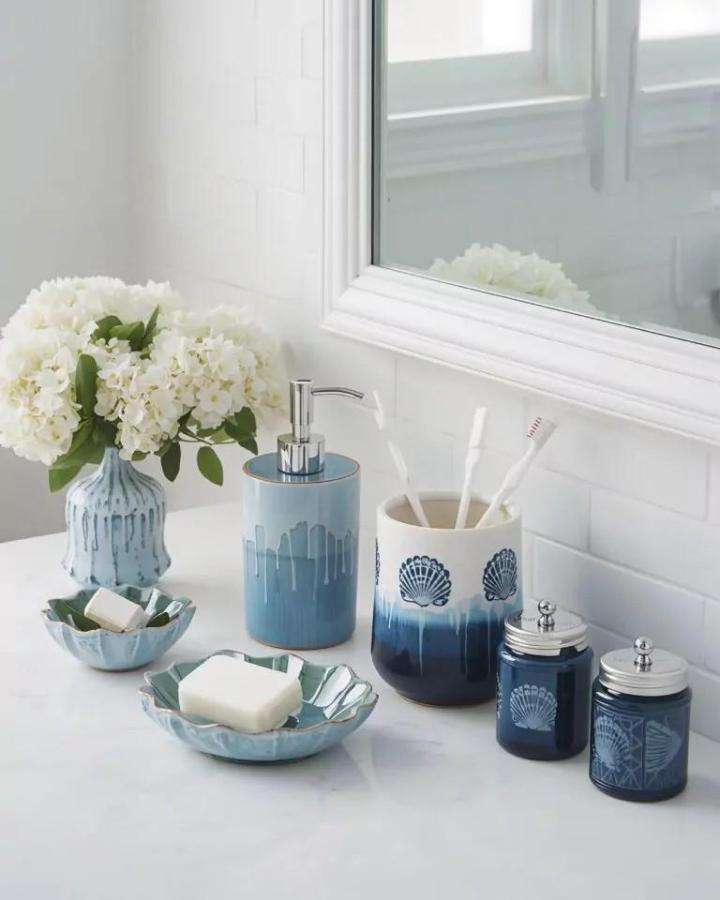 Blue ceramic bathroom accessory collection from Omni Home Ideas including soap dishes and jars with sea shell designs. Soft coastal colors.