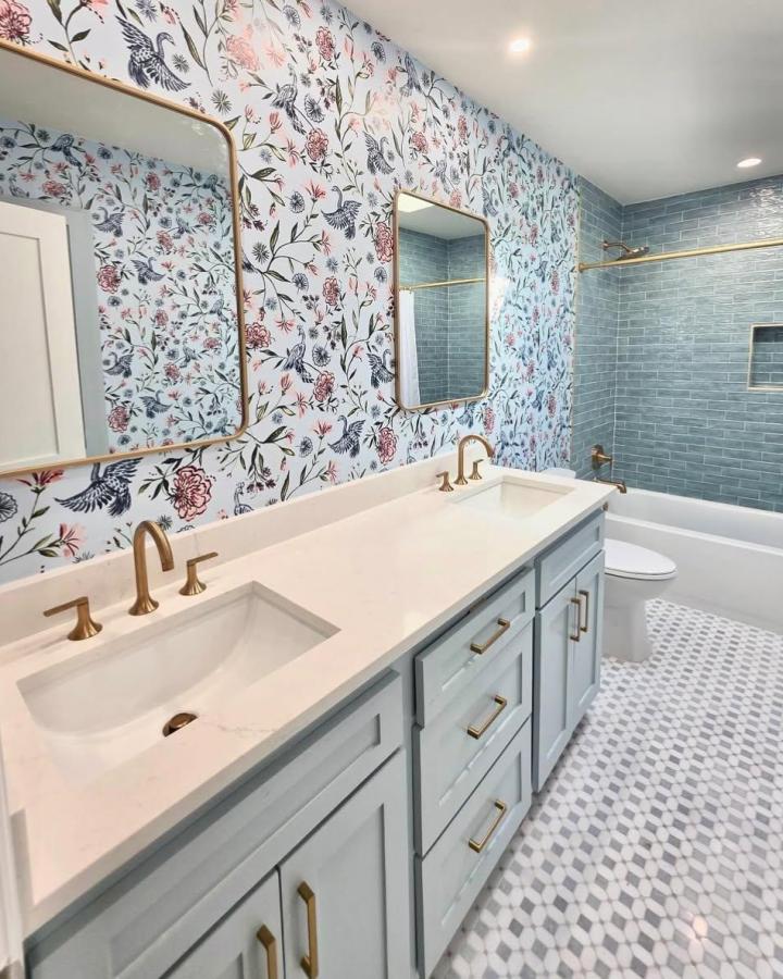 Light blue floral wallpaper bathroom with blue subway tiles and gold hardware from @cozycoutureinteriors, elegant blue bathroom decor ideas.