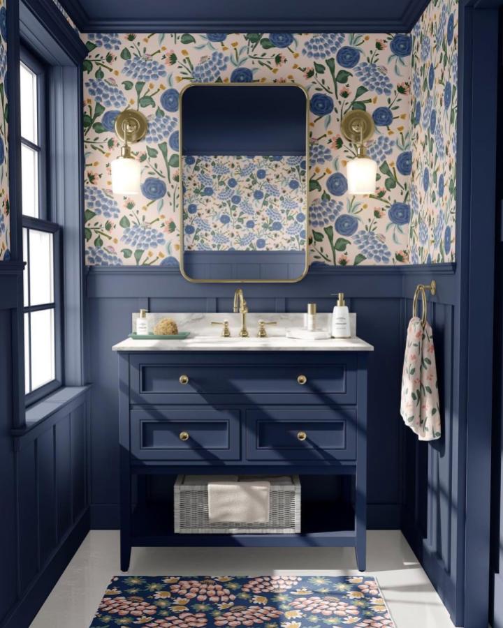 Dusted navy blue bathroom vanity and floral wallpaper from @kaysillustrations bright blue bathroom decor ideas with brass accents and patterned rug