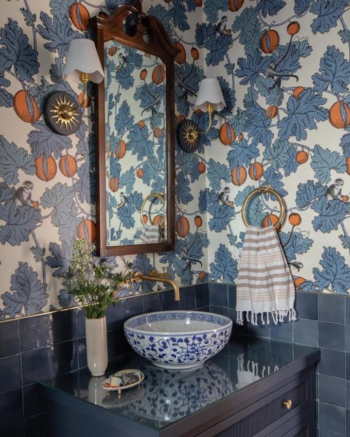 Blue floral wallpaper and Coralie basin in a vintage blue bathroom decor ideas setup by @joannabauminteriors with brass fixtures and dark tiles.