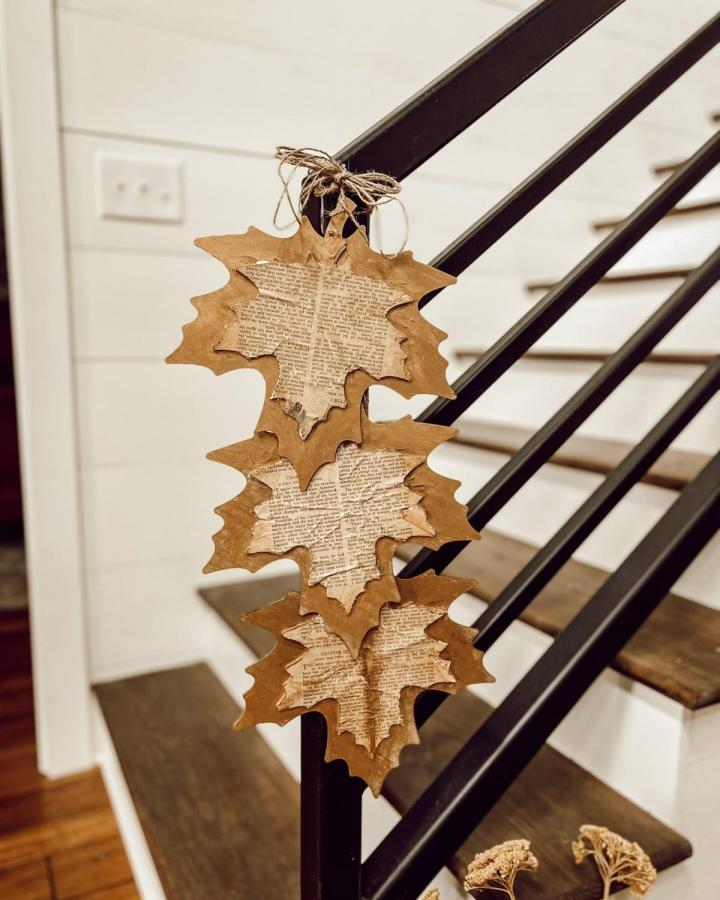 Brown and vintage book page layered leaf collage hanging on black stair railing book page home decor crafts from The Ponds Farm House rustic autumn decoration.
