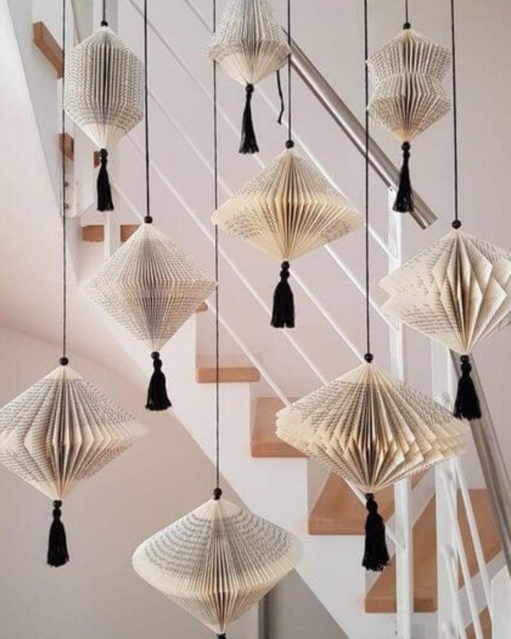 Vintage folded book page lanterns hang with black tassels by 1 Million Ideas. Creative book page home decor crafts with geometric shapes and texture.