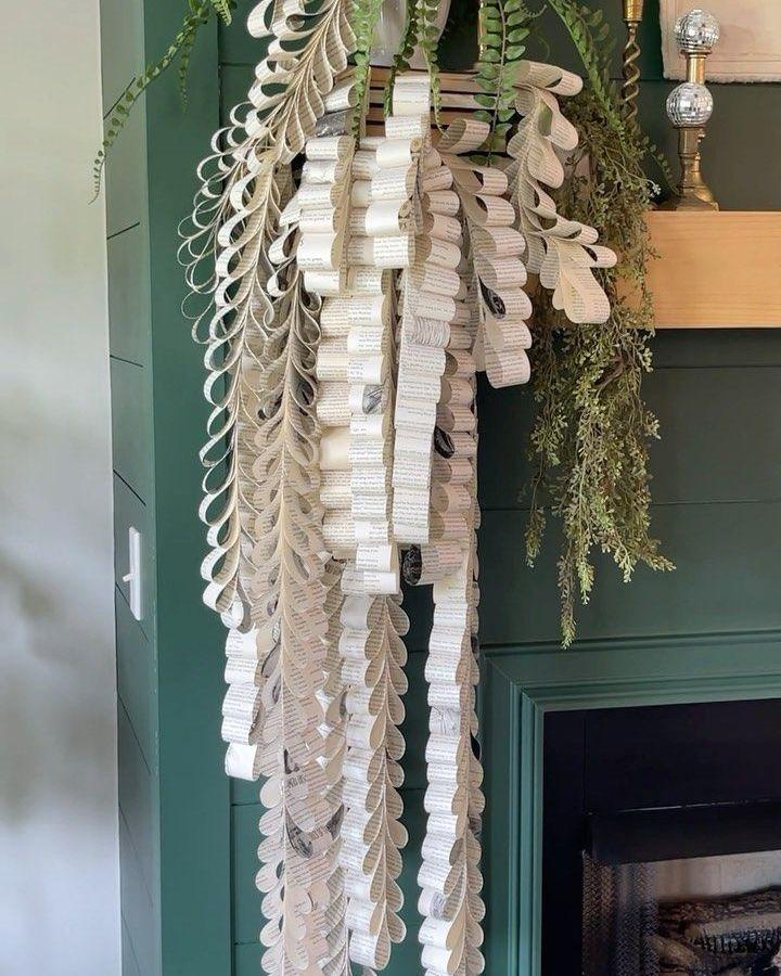 Vintage cream paper leaf garland from @theshabbycreekcottage made with book page home decor crafts hanging by green wall with fireplace.
