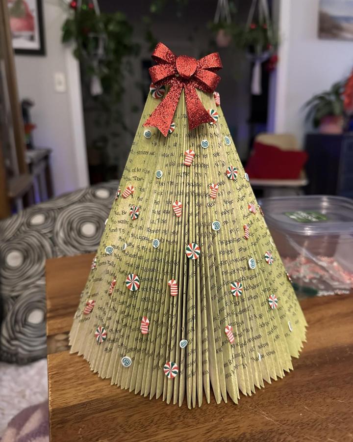 Folded vintage book page Christmas tree with candy decorations and red glitter bow for book page home decor crafts by Robyn Doppke.