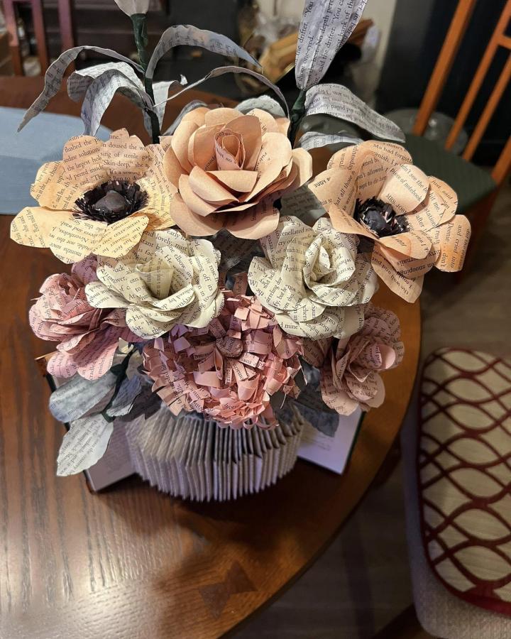 Soft pastel paper flower bouquet with folded book vase from Catherine Davis. Vintage text petals and curled leaves create charming book page home decor crafts.