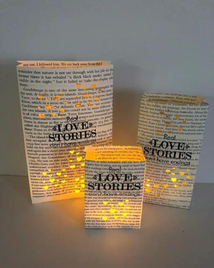 Yellow glowing lanterns made from book page home decor crafts by Emmaline Bride showcasing love stories cutouts and soft light.