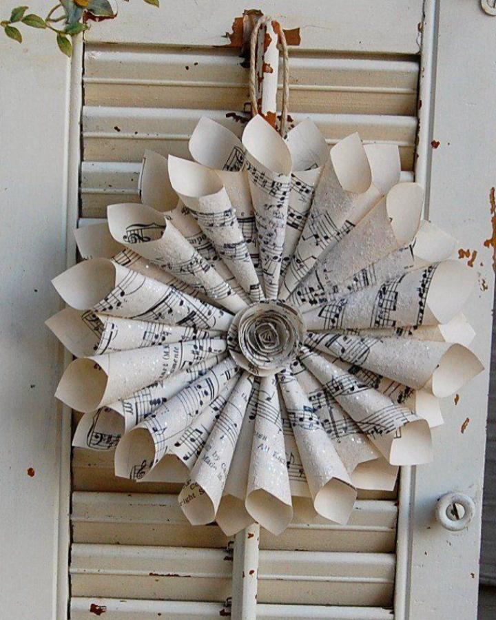 Rolled sheet music wreath from Adventures in Futility and Knitting decorated with white glitter for book page home decor crafts.