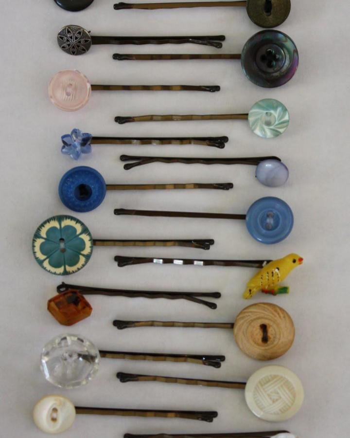 Colorful and vintage button adorned hairpins laid out on white surface showing button crafts for adults creative ideas.