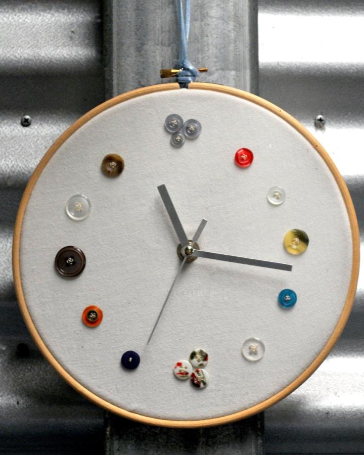 Brown, blue, red buttons on white fabric clock face in embroidery hoop from epherielldesigns. Button crafts for adults timepiece.