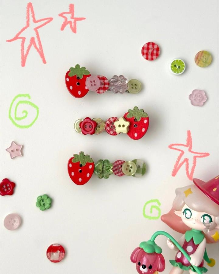 Red and green strawberry button hair clips with floral and geometric buttons from @starrfruityy. Playful button crafts for adults.