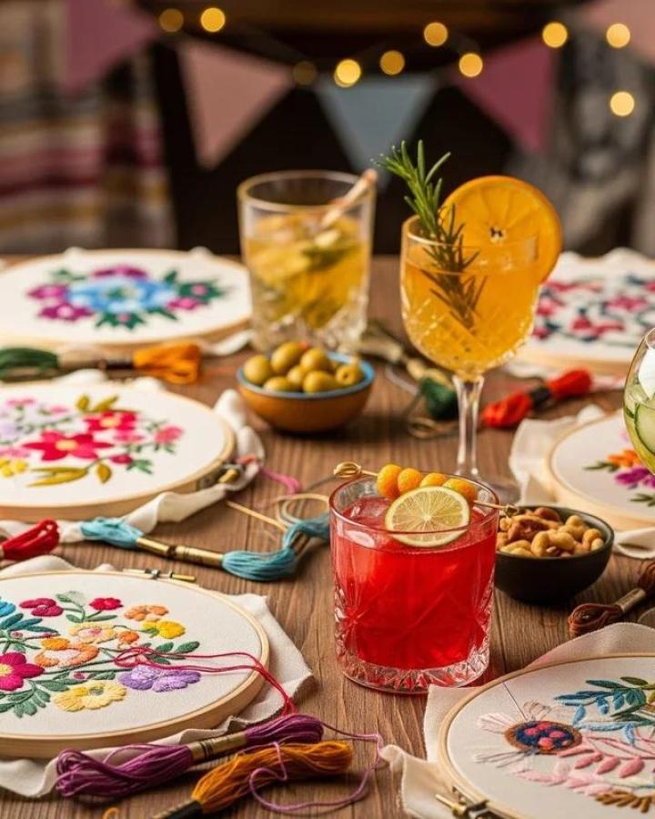 Colorful floral embroidery hoops laid out with threads, snacks, and drinks for craft night themes for adults inspiration from DIY Doer. Cozy, creative setup.