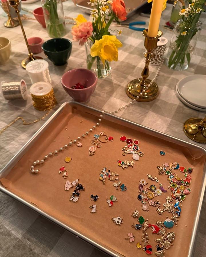 Colorful enamel charms and delicate wire on a baking tray by @ashleylaurentassano for craft night themes for adults with a cozy table setting and floral accents