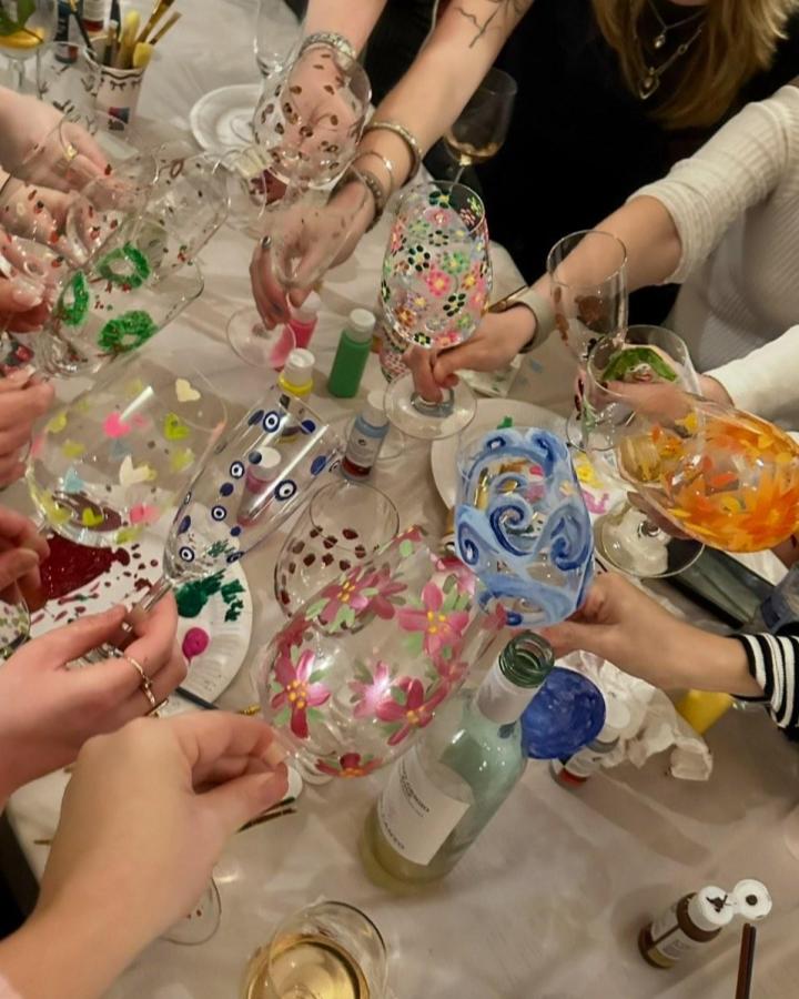 Colorful hand-painted wine glasses with floral and swirl designs from @surreygirlssocials. Creative craft night themes for adults project.
